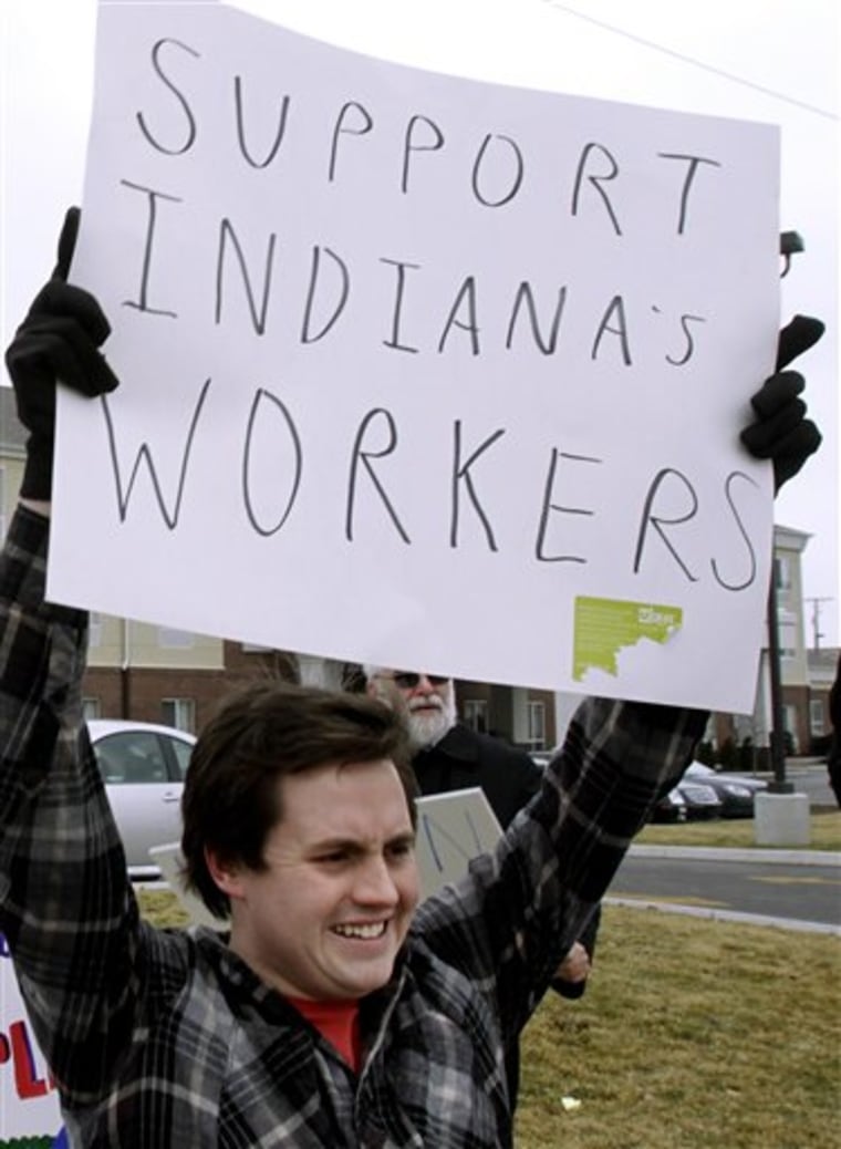 A pro-union demonstrator shows a sign to passing drivers outside the Comfort Suites in Urbana, Ill., on Thursday. About 30 Democratic members of the Indiana House of Representatives are staying at the hotel after fleeing Indianapolis this week to avoid voting on labor- and education-related legislation they oppose.